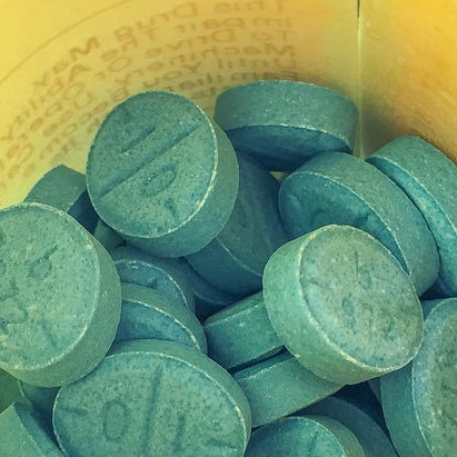 Green Adderall pills in a prescription bottle. Green Adderall pills in a prescription bottle.