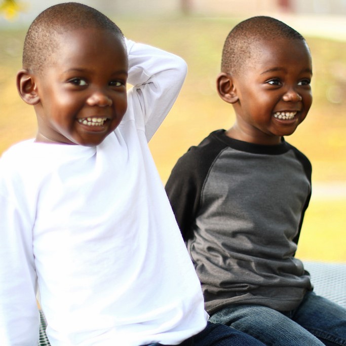 Two young twin brothers sit together and smile. Two young twin brothers sit together and smile.