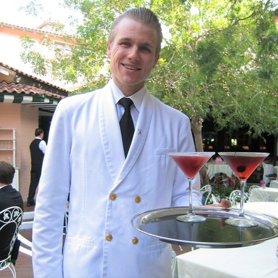 A smiling waiter delivering cocktails on a tray. A smiling waiter delivering cocktails on a tray.