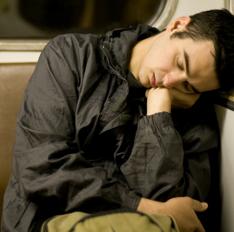 A mans sleeps in his seat on the bus.