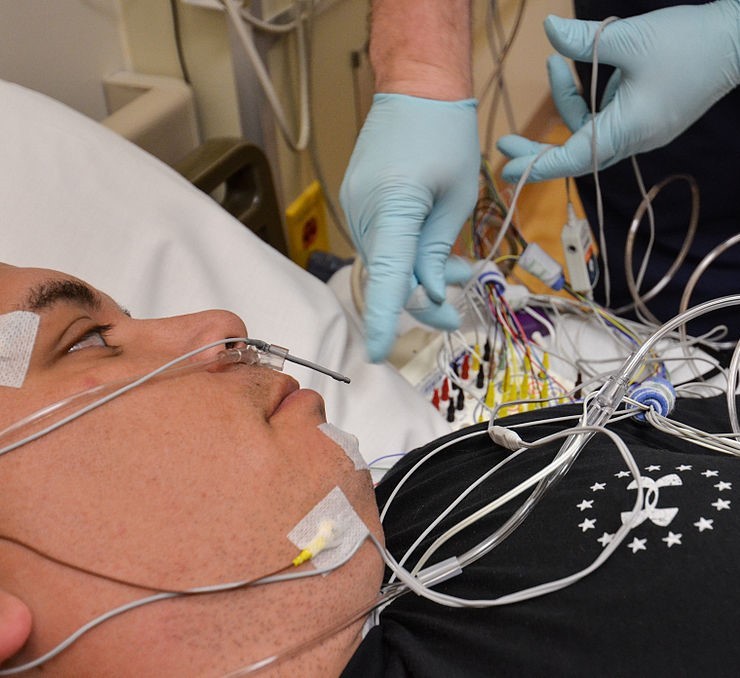 A sleep technician wires a patient for a sleep study. A sleep technician wires a patient for a sleep study.