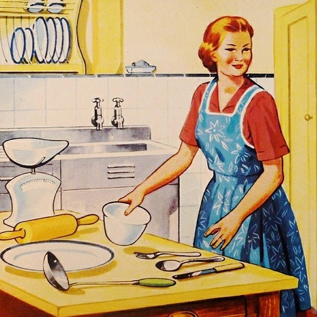 A stereotypical housewife of the 1950s stands in her kitchen wearing an apron with a table full of cooking utensils in front of her. A stereotypical housewife of the 1950s stands in her kitchen wearing an apron with a table full of cooking utensils in front of her.