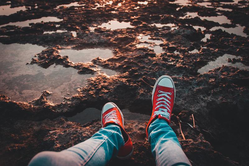 Image of a person sitting at the edge of a muddy puddle.